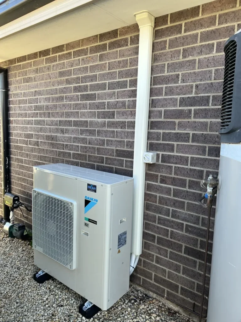 Outdoor air conditioning unit next to brick wall.