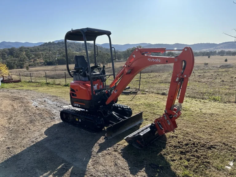 Kubota mini excavator on scenic farmland.