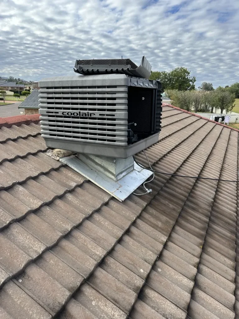 Roof-mounted air conditioning unit on tiled roof.